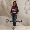 A woman in a purple hoodie standing in front of a wall, reviewing call center software.