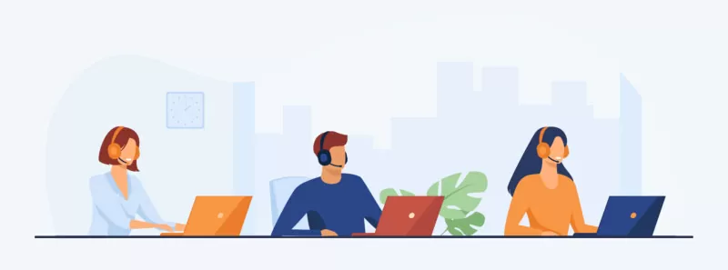 Call center representative wearing headphones and sitting at a desk with laptops 